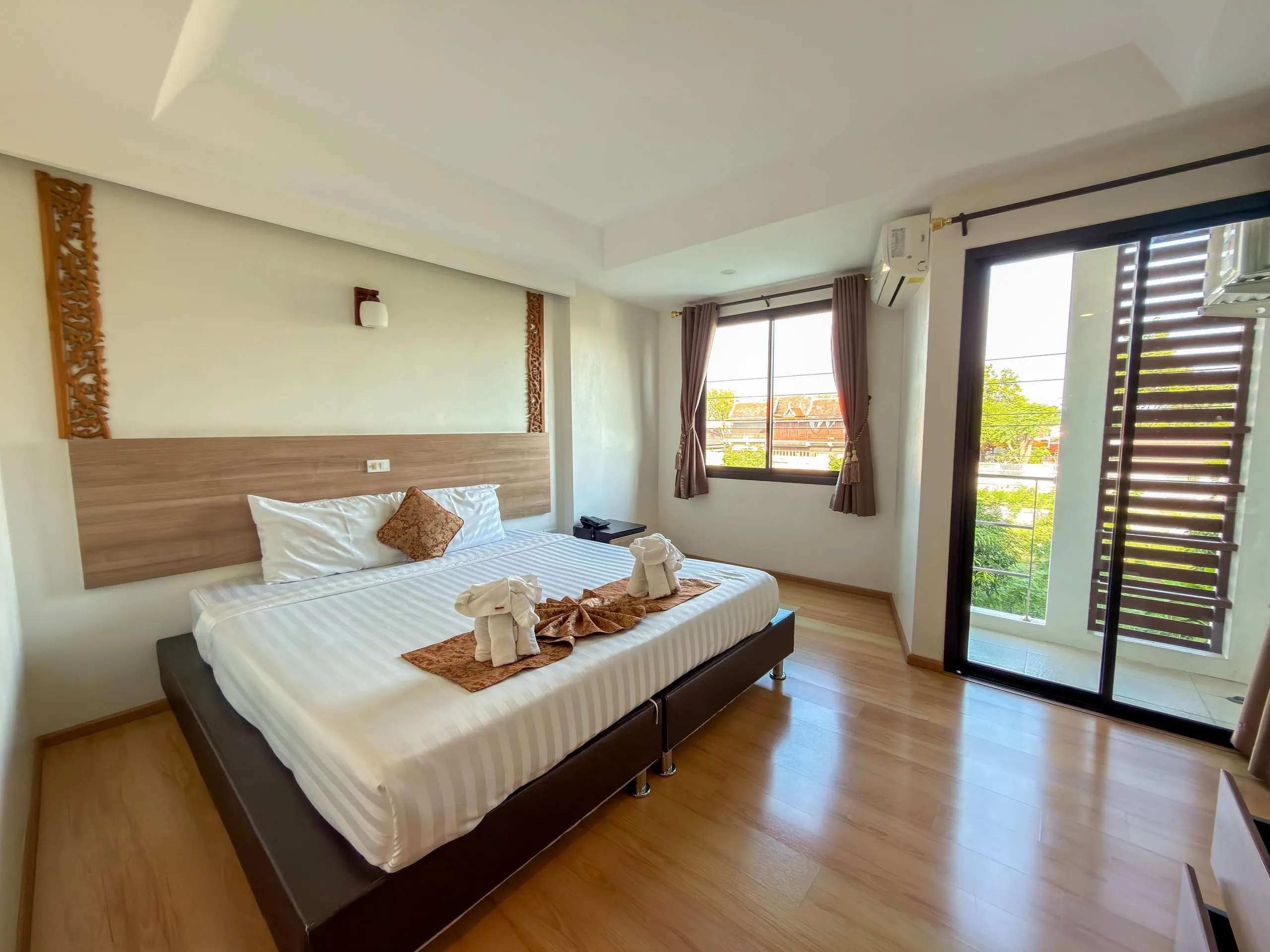 Standard King room: king bed with a wooden headboard, window and balcony door