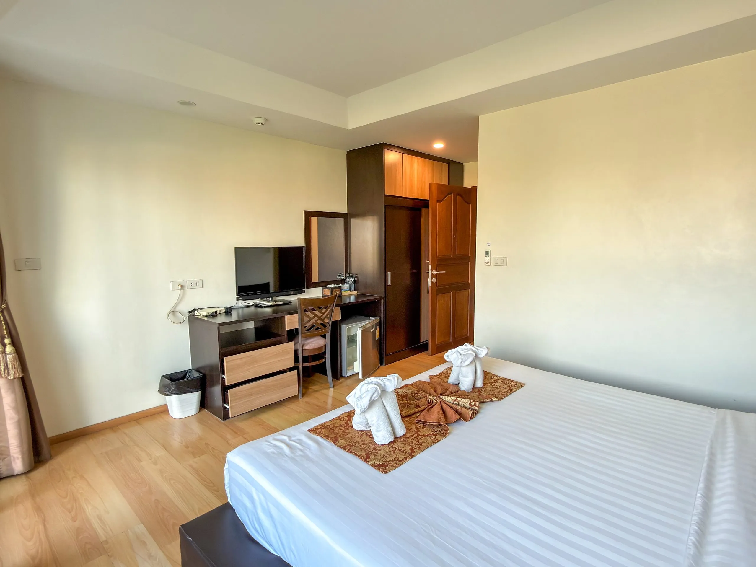 Standard King room: work desk with TV and mini fridge, bed with towel elephants in front