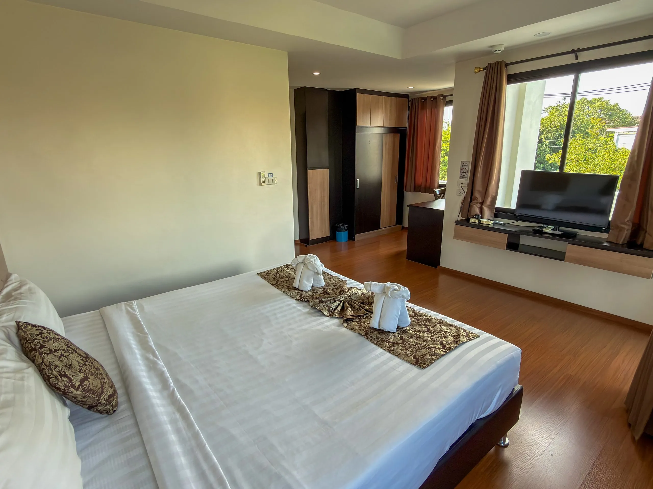 Superior King room: king bed with towel elephants, TV by the window and wardrobe