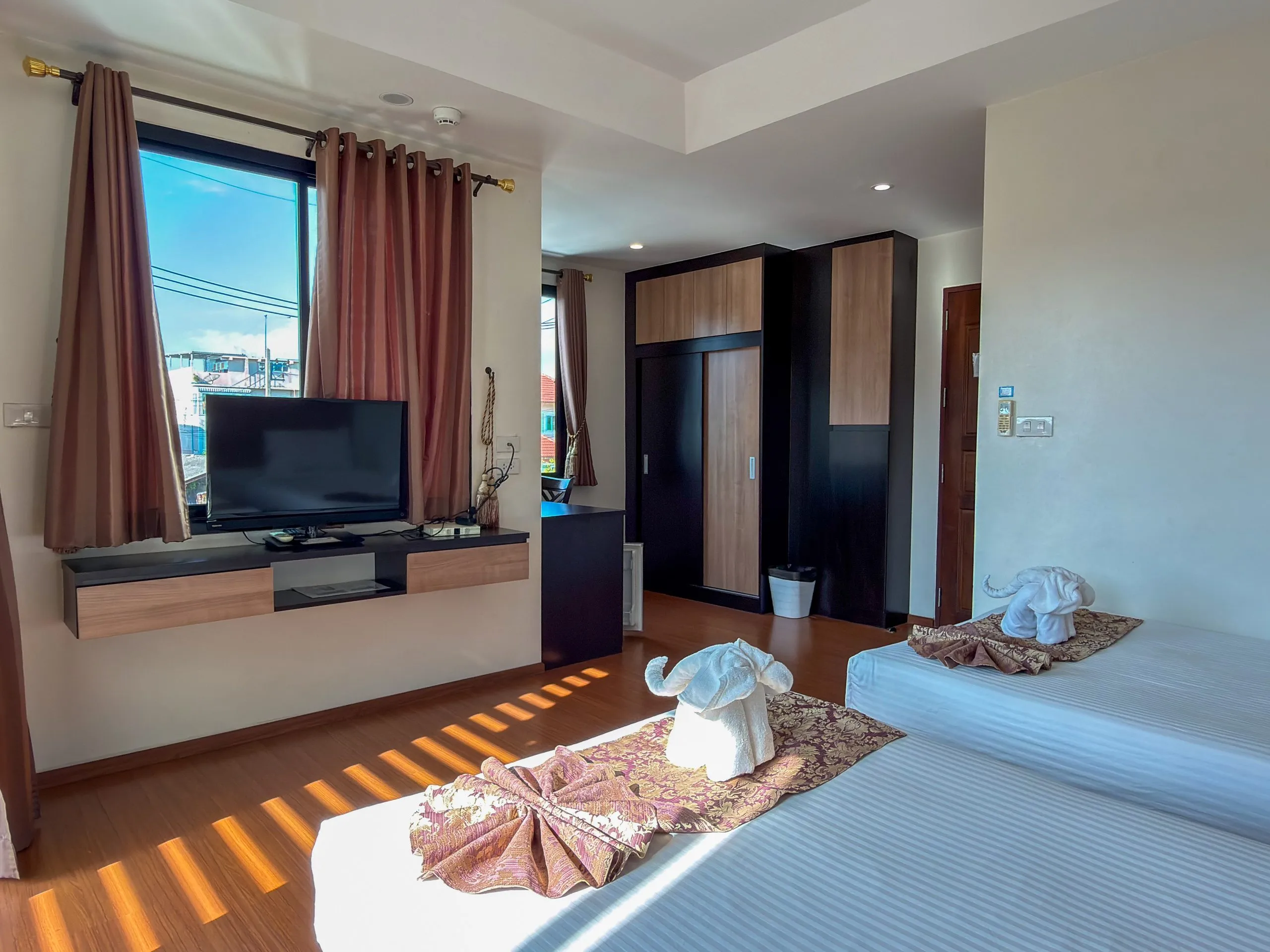 Superior Twin room: TV on a wall shelf and wardrobe, single bed with a towel elephant in front