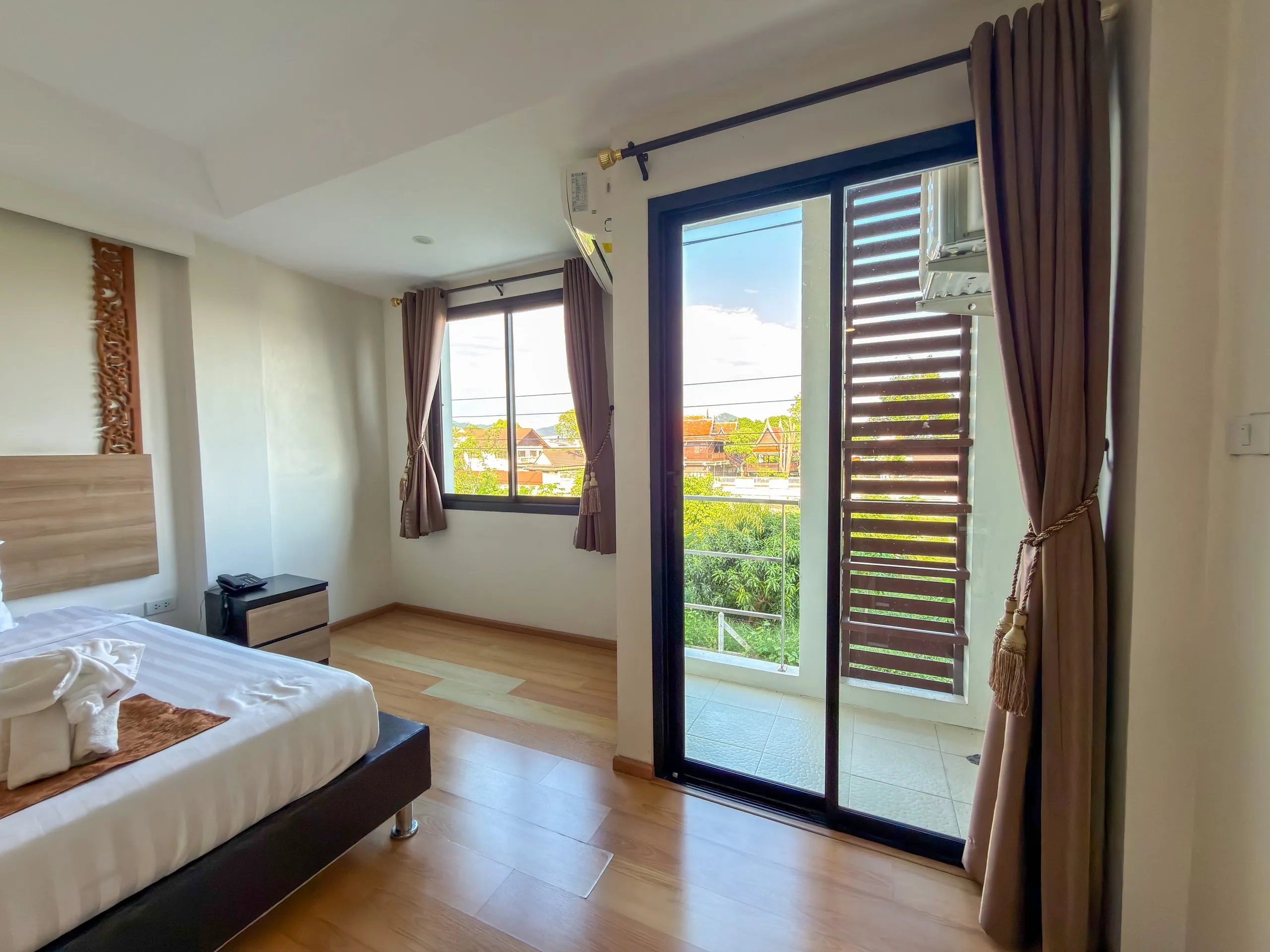 Standard King room: bed with a towel elephant beside the window and balcony door