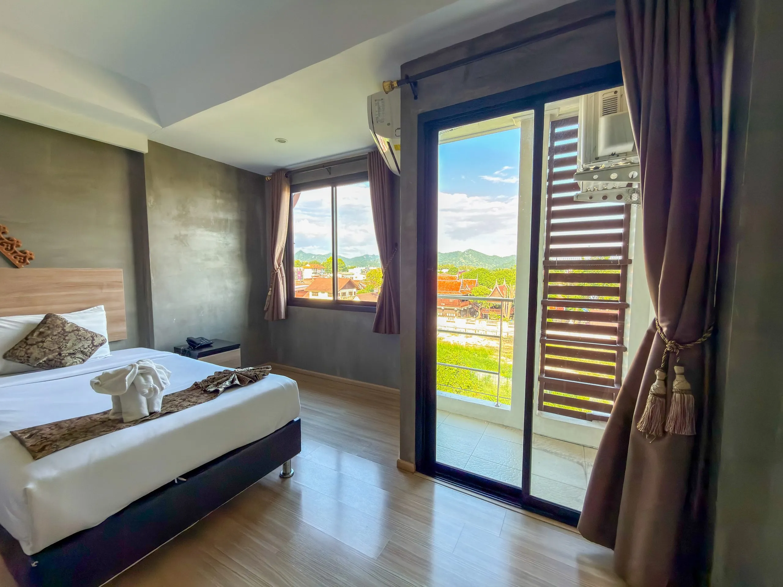 Standard Twin room: single bed with a towel elephant, window and balcony door with a view