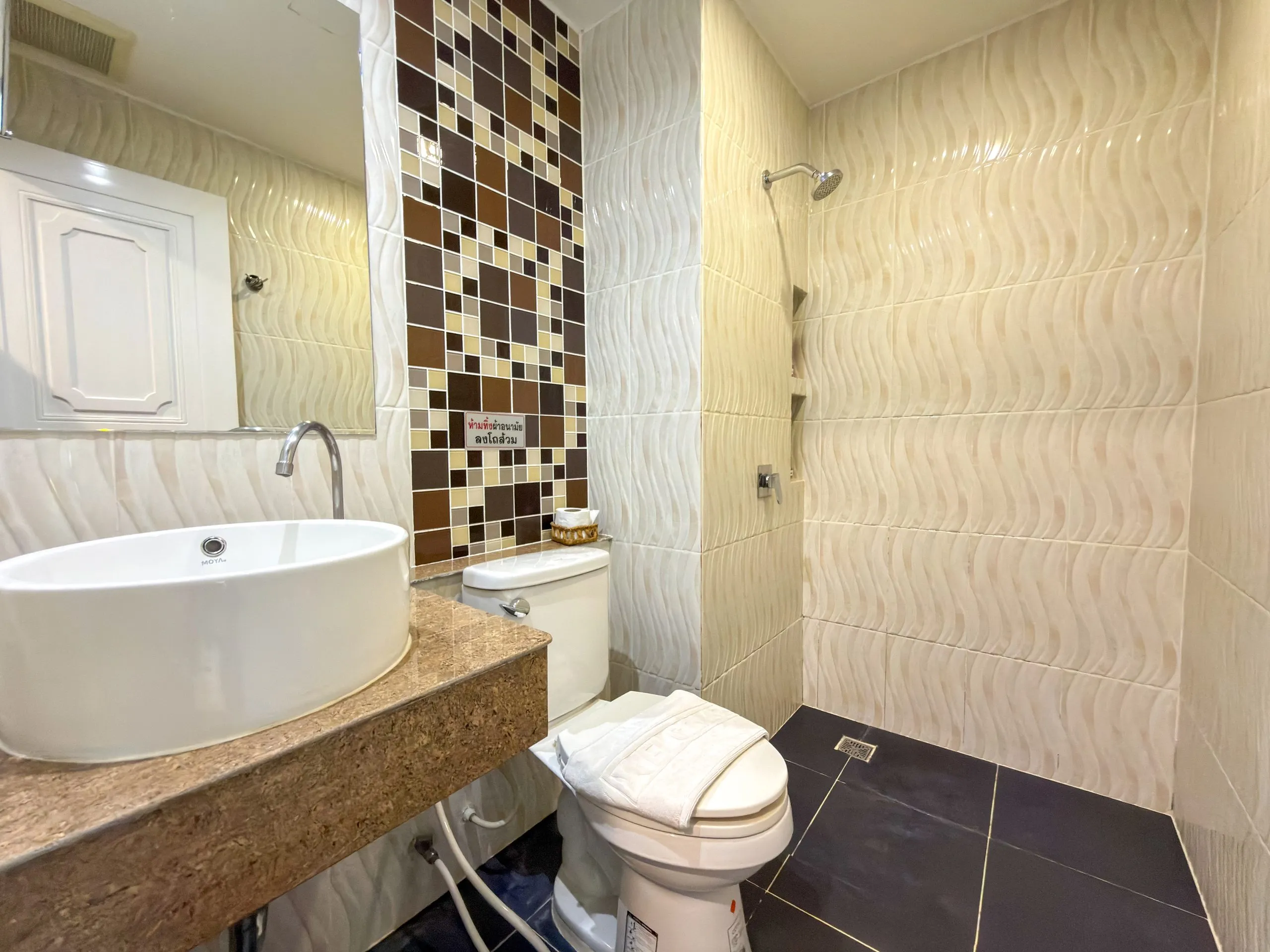 Standard King room bathroom: basin, toilet and walk-in shower with wave-pattern tiles