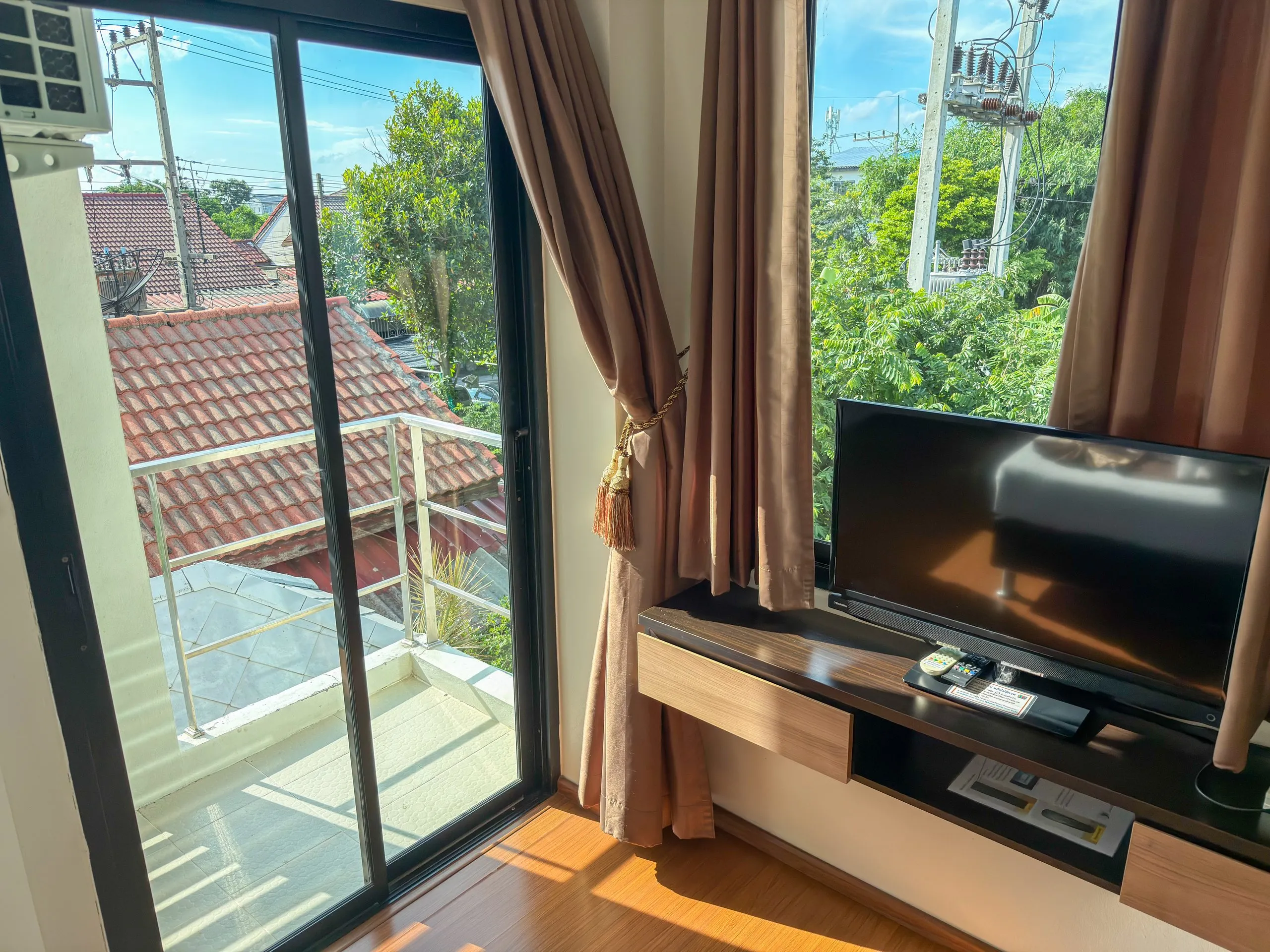 Superior Twin room: balcony sliding door, curtains and TV on a floating shelf