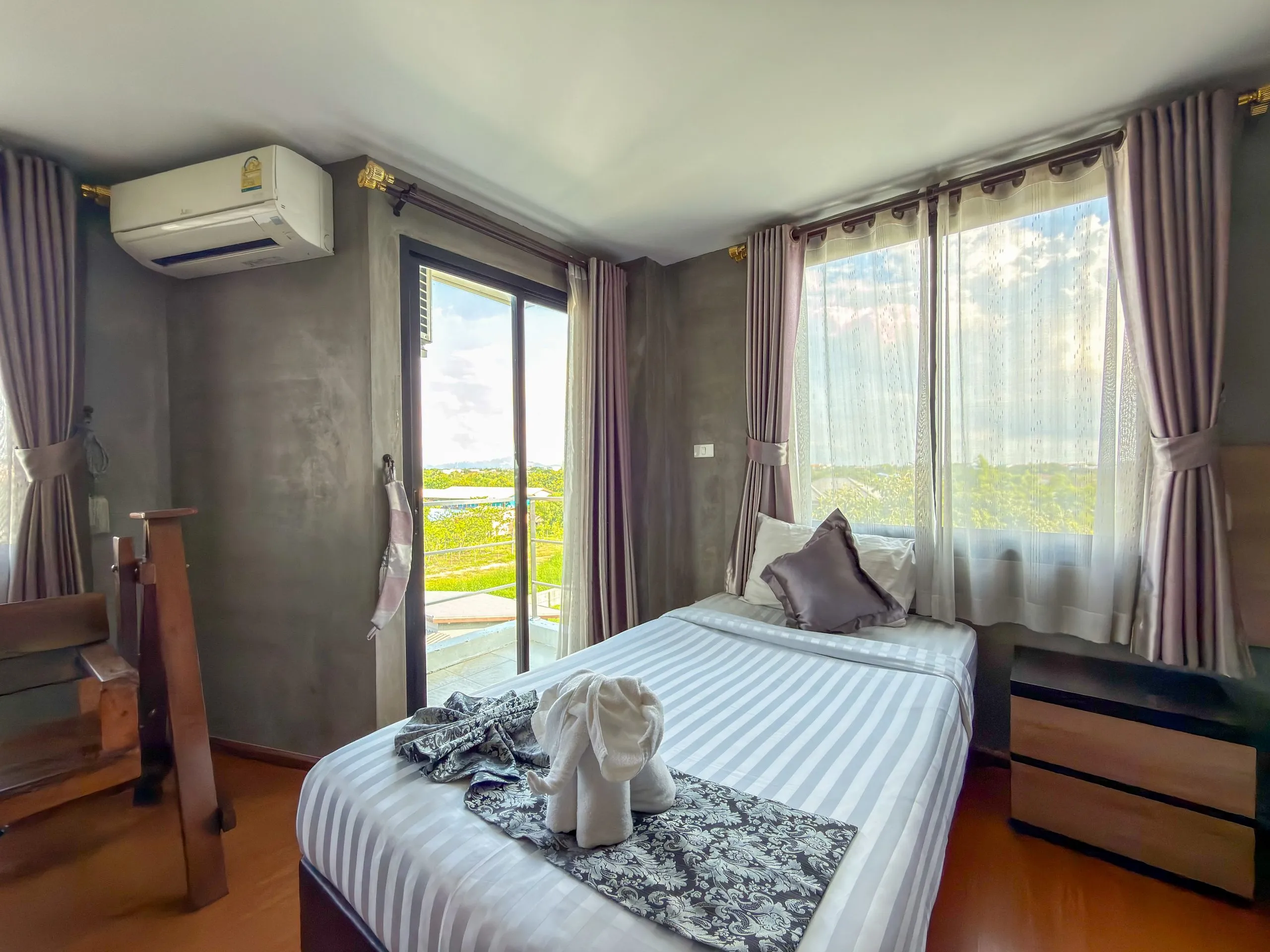 Studio: single bed with a towel elephant beside the window and balcony door